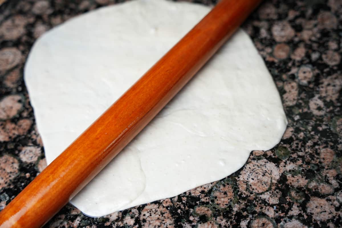 Parotta dough rolled flat. A rolling pin is on top.