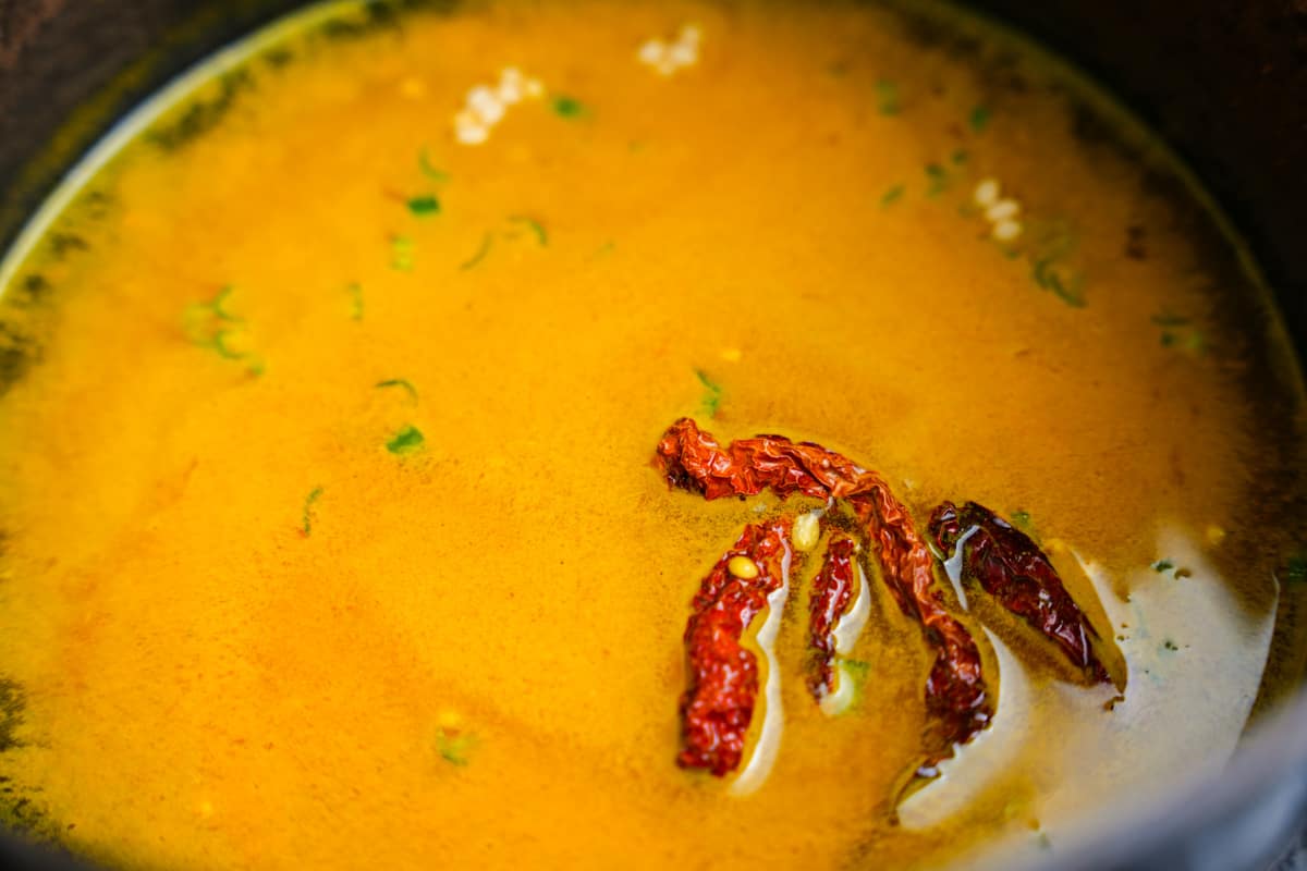 A pot bringing the dal, water, chilies and turmeric up to a boil.