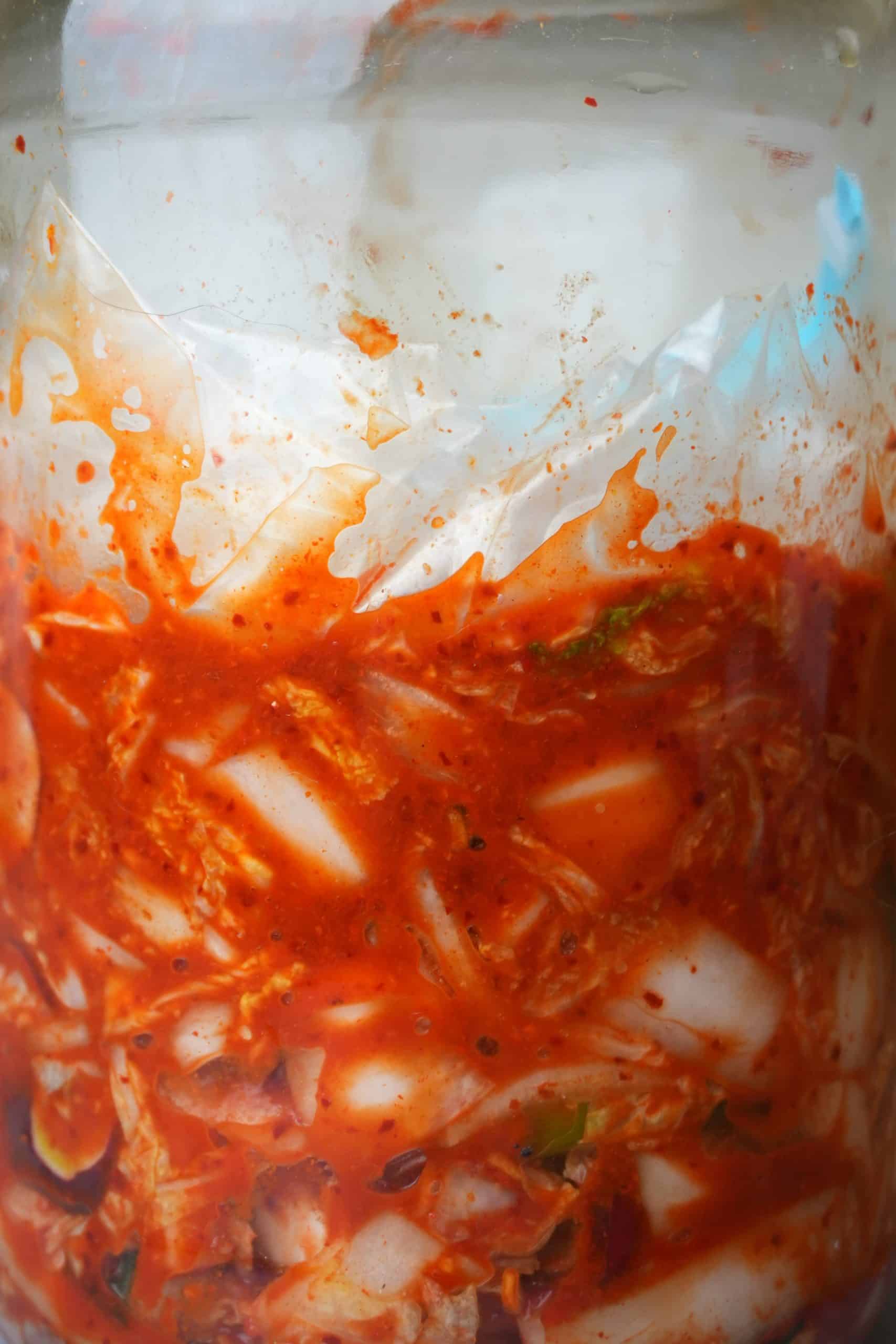 Plastic on the top layer of the of vegan kimchi in a jar.