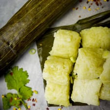 Cut pieces of compresed rice cakes on a piece of banana leaf. A still-wrapped lontong is in the background.