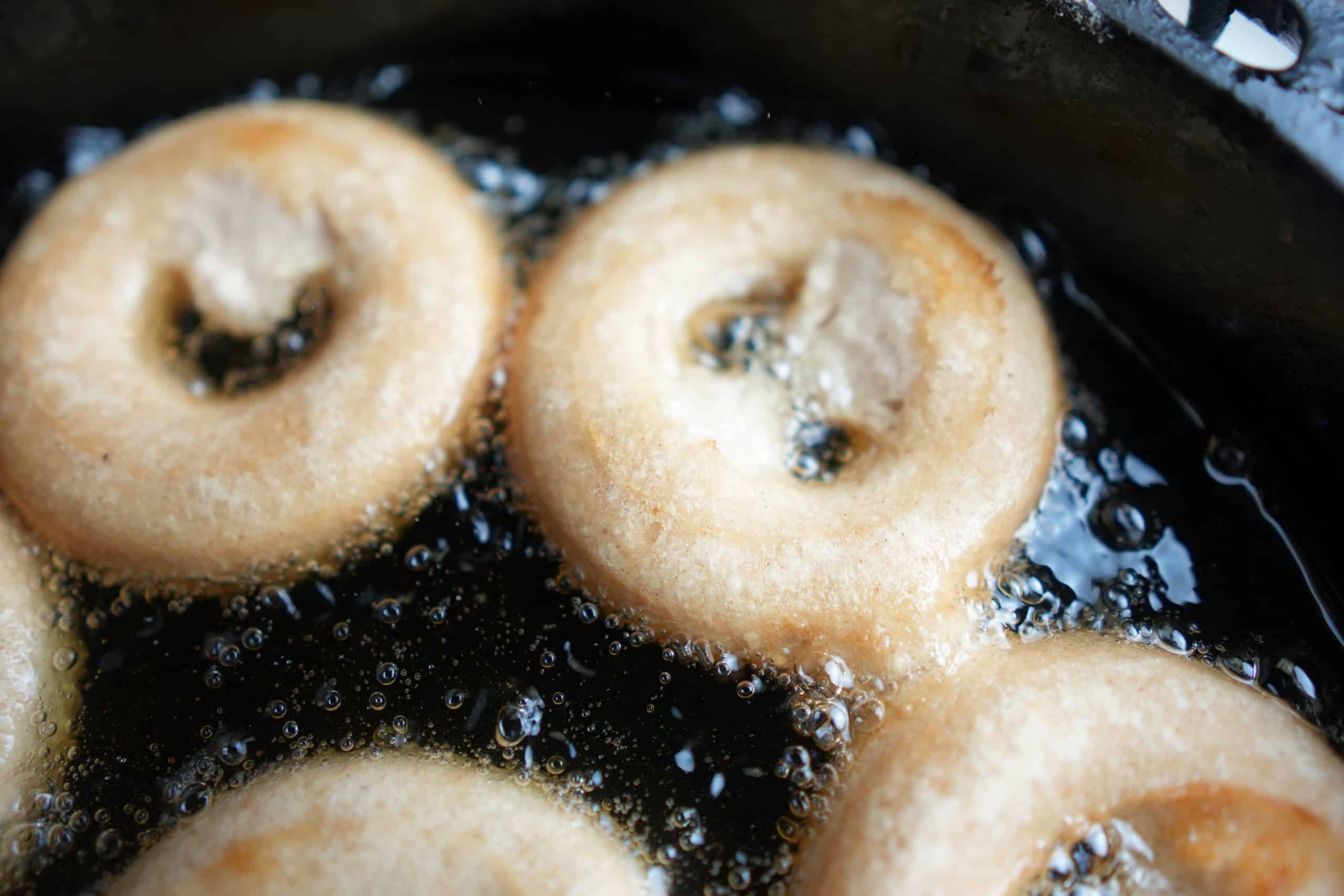Vegan apple cider donuts fried in a pan.