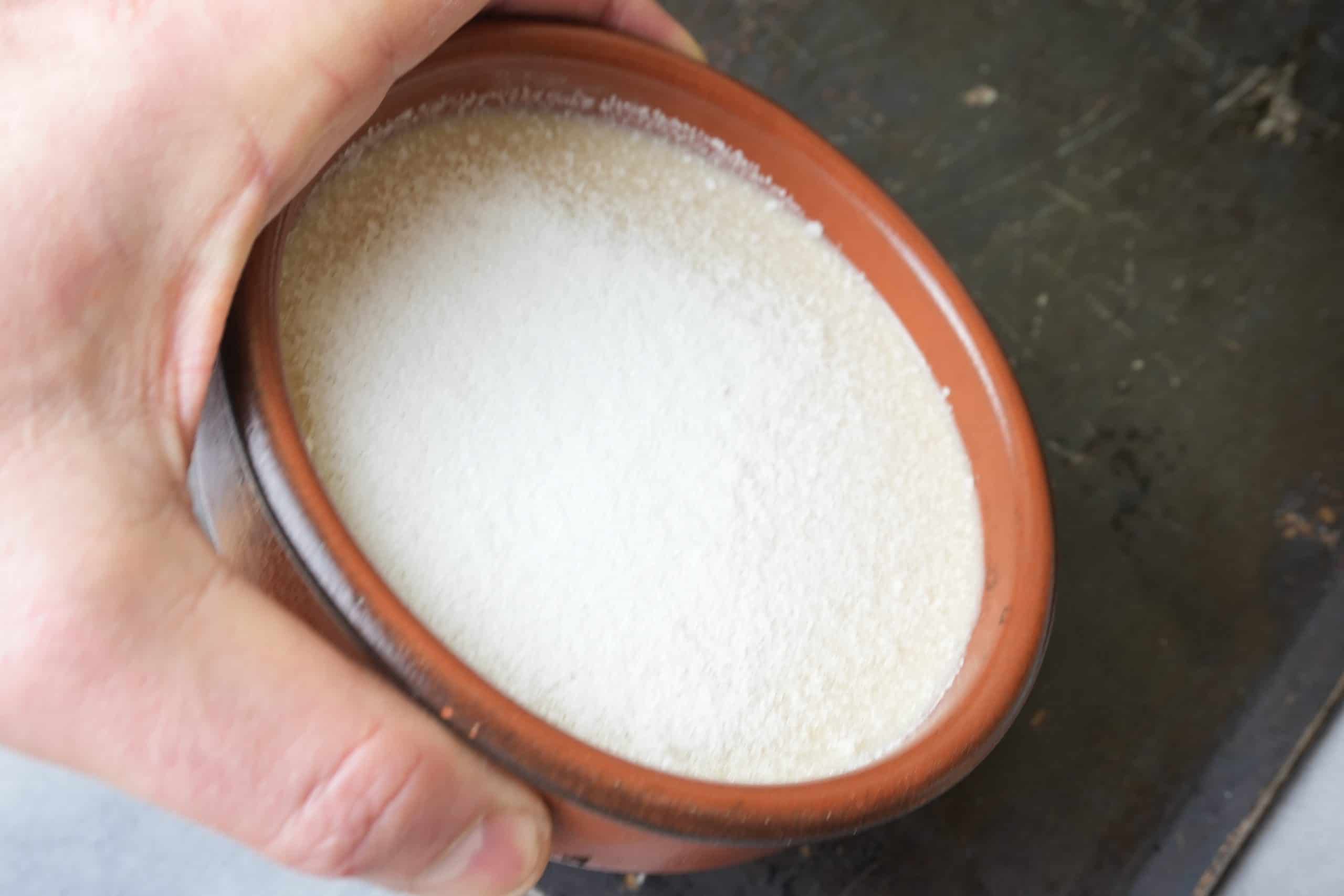 sugar being spread around a ramekin by tilting
