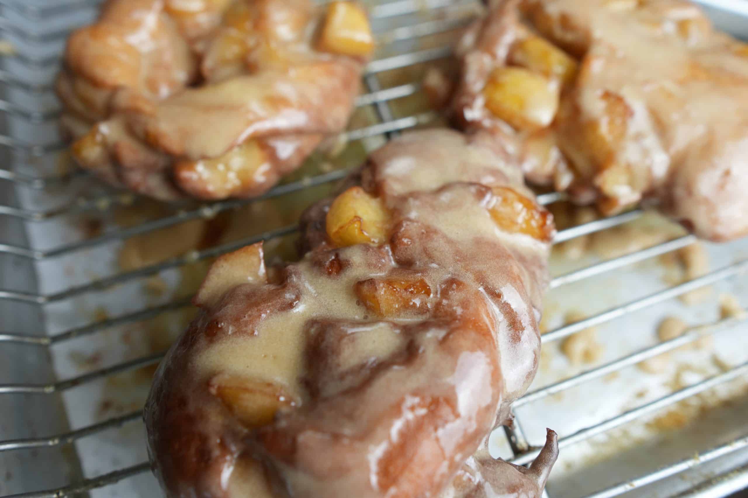 glazed apple fritters cooling on a wire rack.