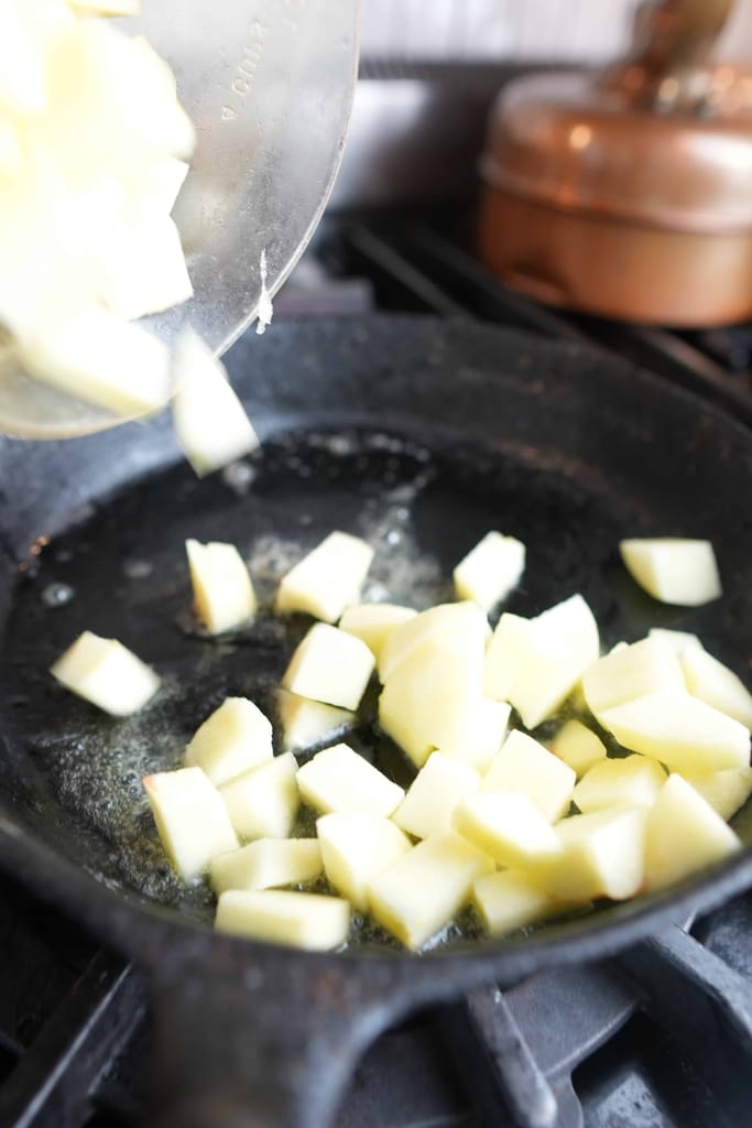 adding the cut apples to a frying pan with vegan butter