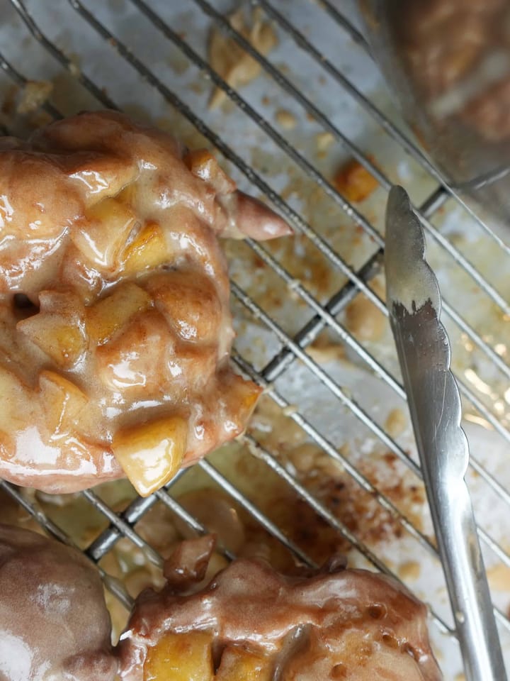 apple fritters cooling on a wire rack after being glazed