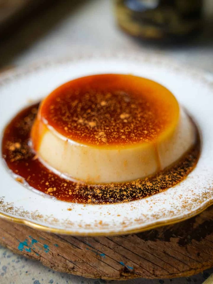 A cinnamon dusted serving of banh flan on a plate.