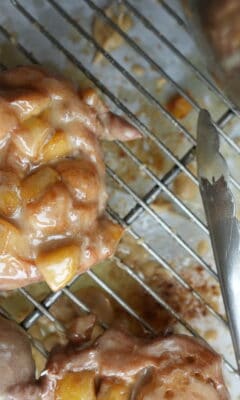 apple fritters cooling on a wire rack after being glazed