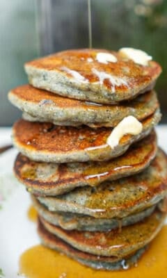 A stack of vegan blue corn pancakes with syrup on a plate.
