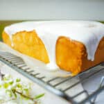 Frosted vegan pound cake cooling on a wire rack.