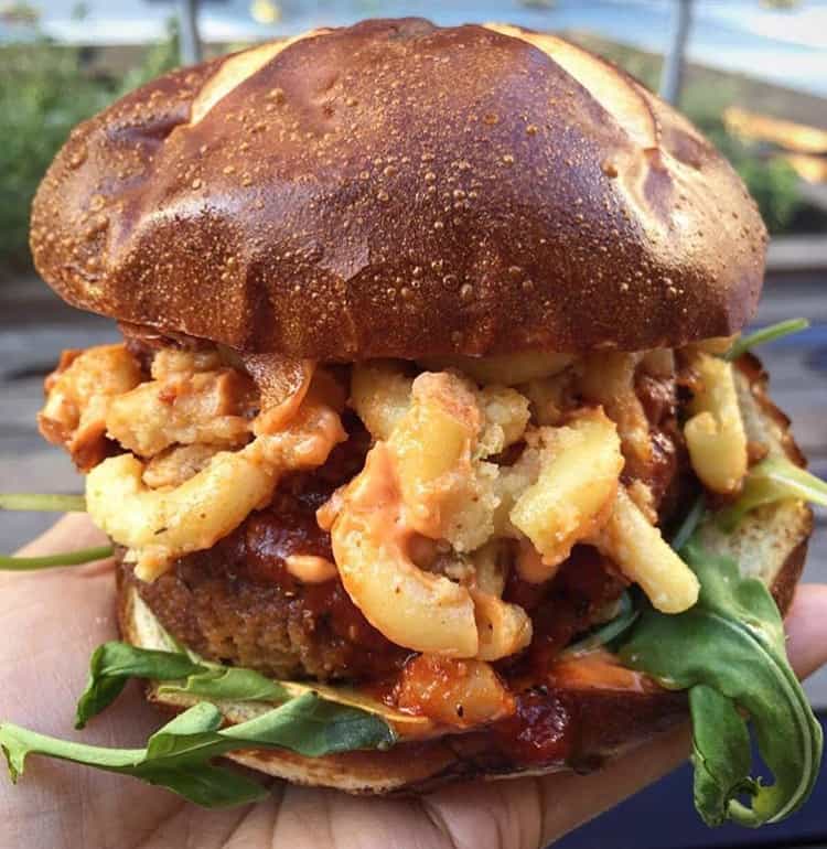 Giant vegan burger with mac n cheese on a pretzel bun.