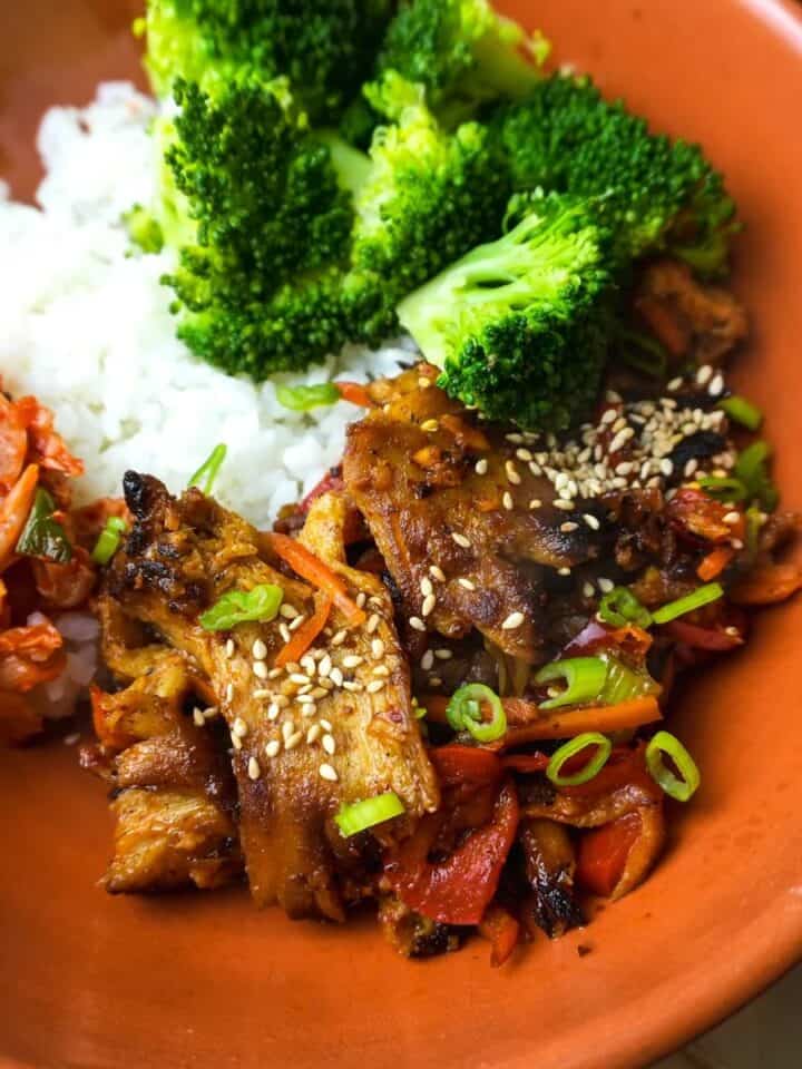 Vegan bulgogi with shortgrain rice and steamed broccoli in a white bowl. Kimchi and chopsticks on the side.