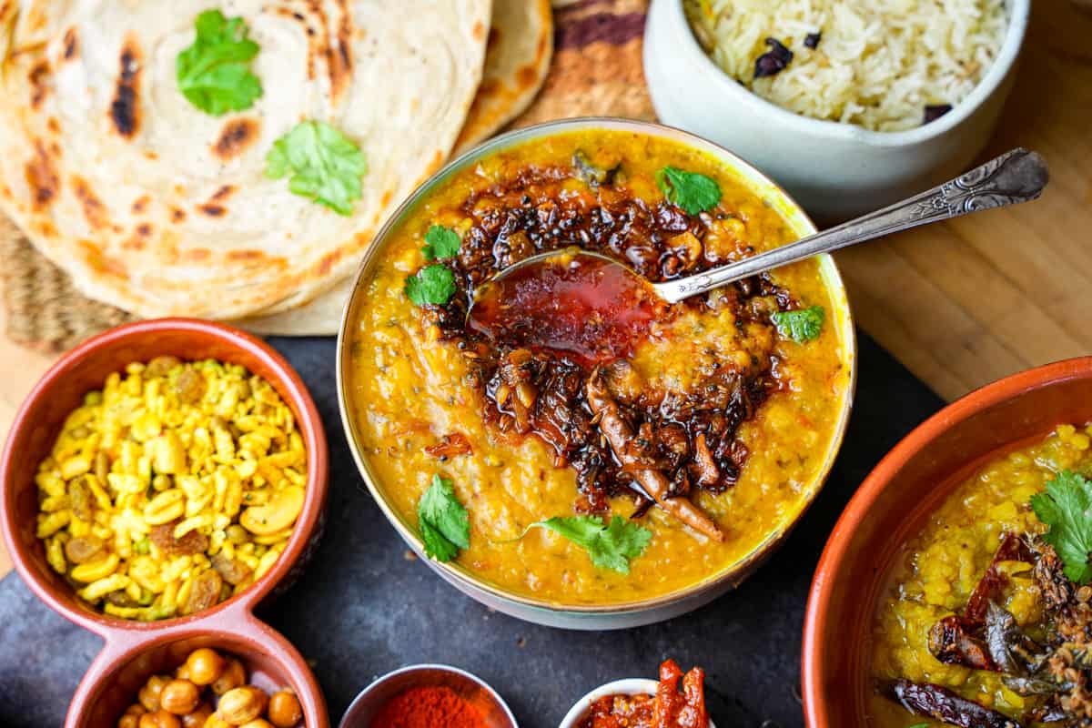 Arhar Dal with a spoon seen from above. Roti, rice and condiments on the side.