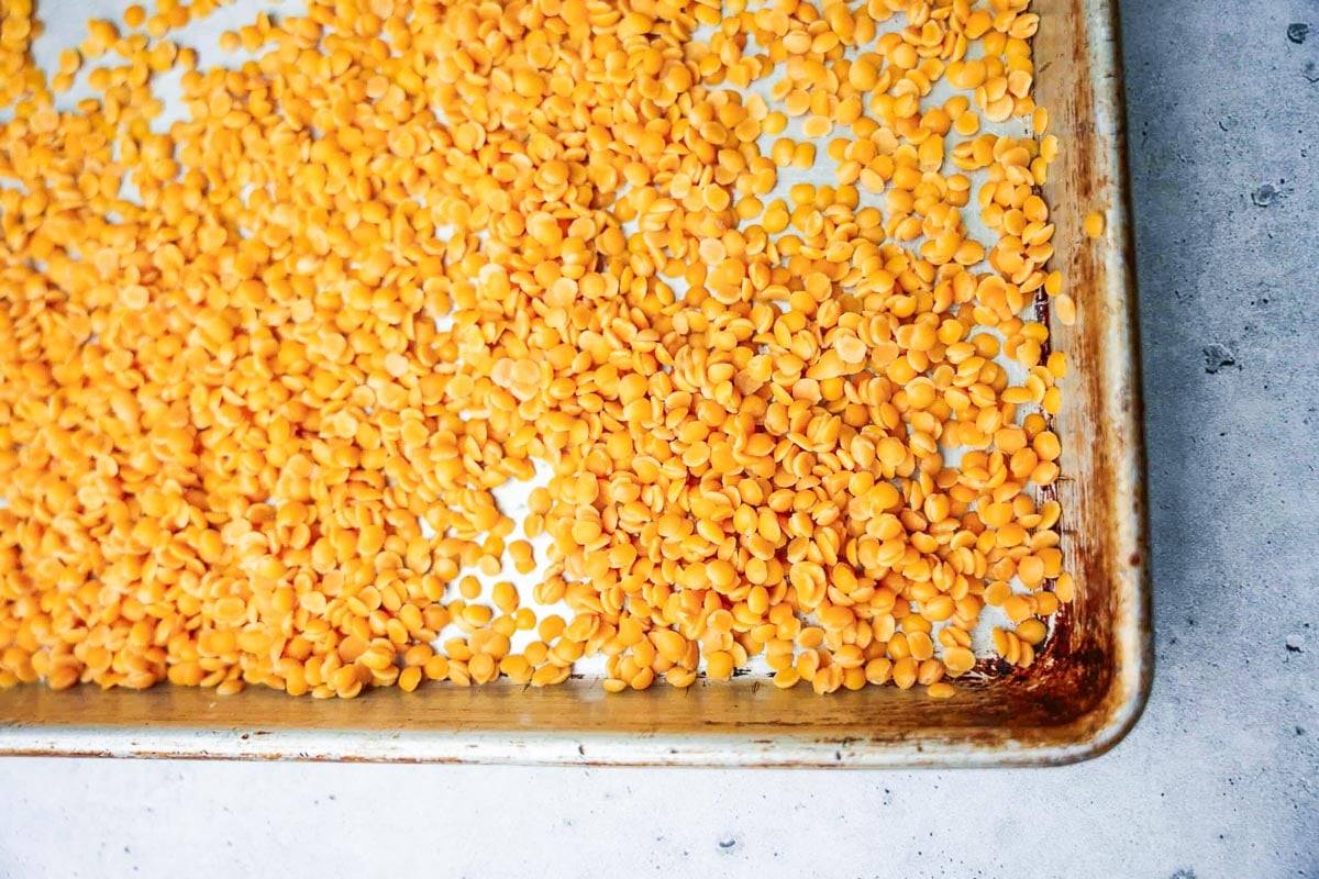 A baking tray filled with evenly spread arhar dal, showcasing its rich, golden hue.