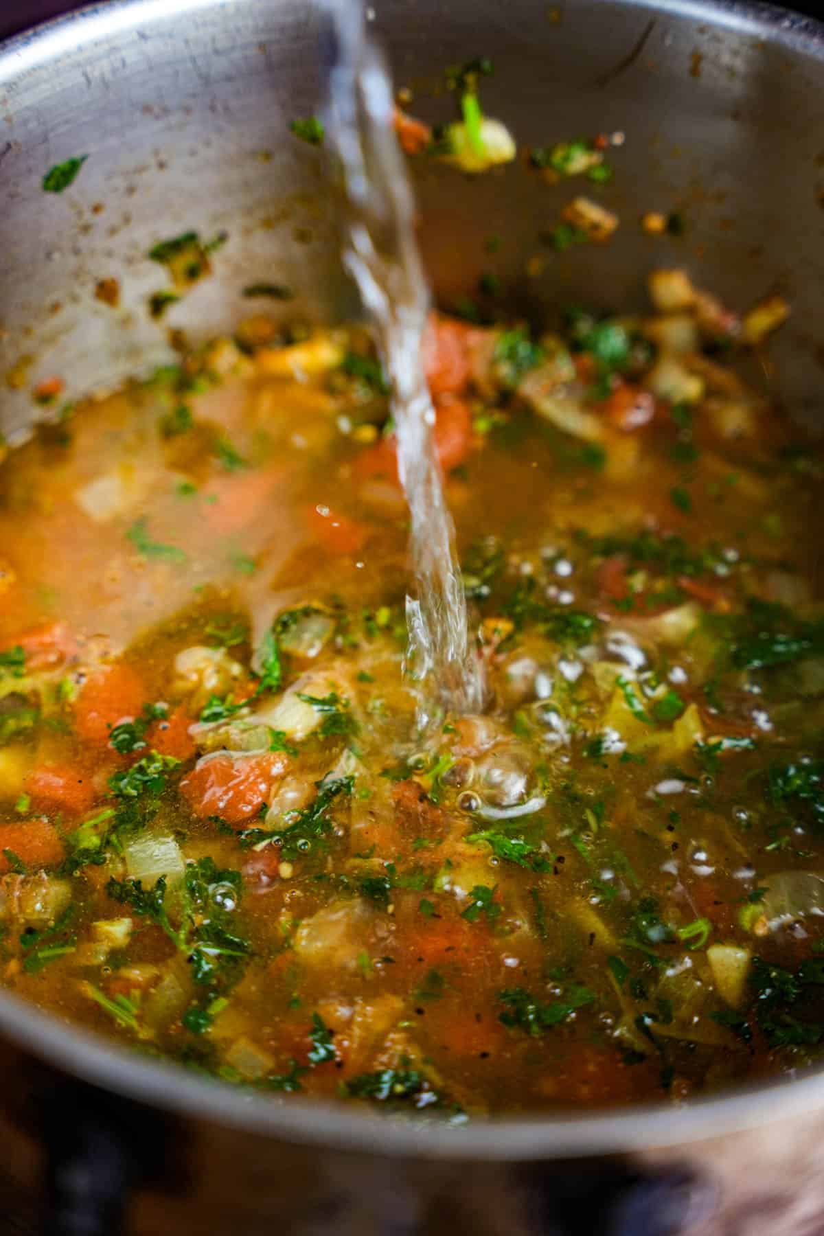 Water is added to the pot of cooking vegetables.