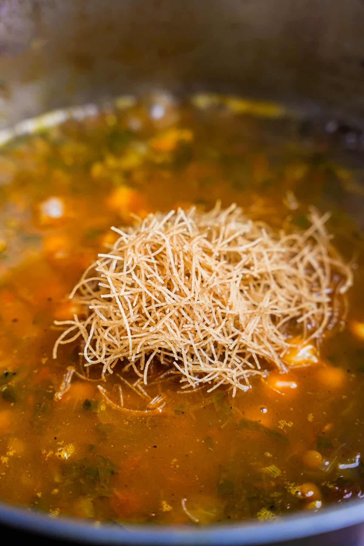Vermicelli is added to the pot of soup.
