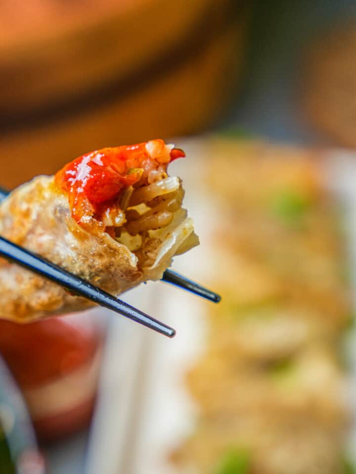 rice dumpling with chili sauce being eaten with chopsticks.