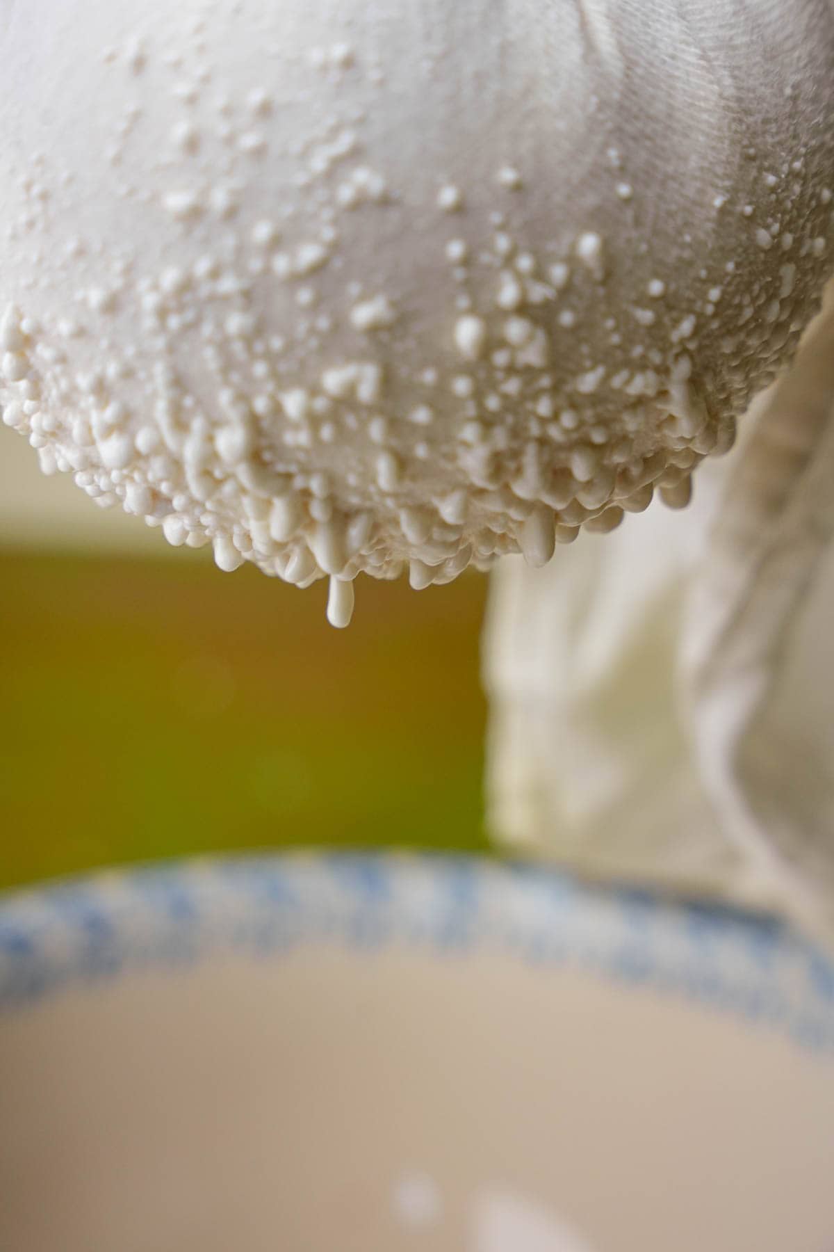 Liquid is shown being strained out of cheesecloth into a ceramic bowl
