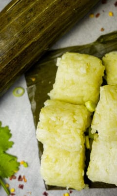 Cut pieces of compresed rice cakes on a piece of banana leaf. A still-wrapped lontong is in the background.