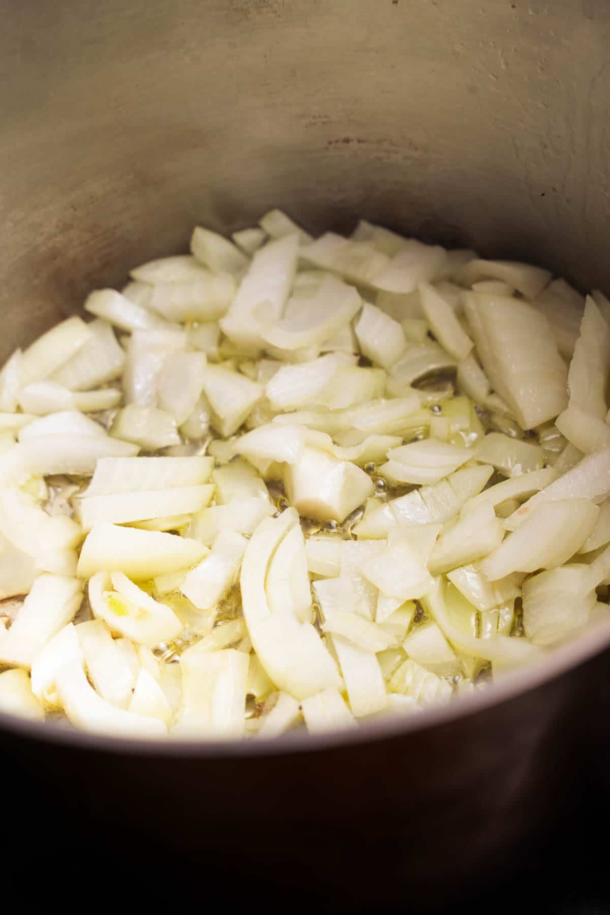 Diced onions sauté in hot oil in a stainless steel pot.