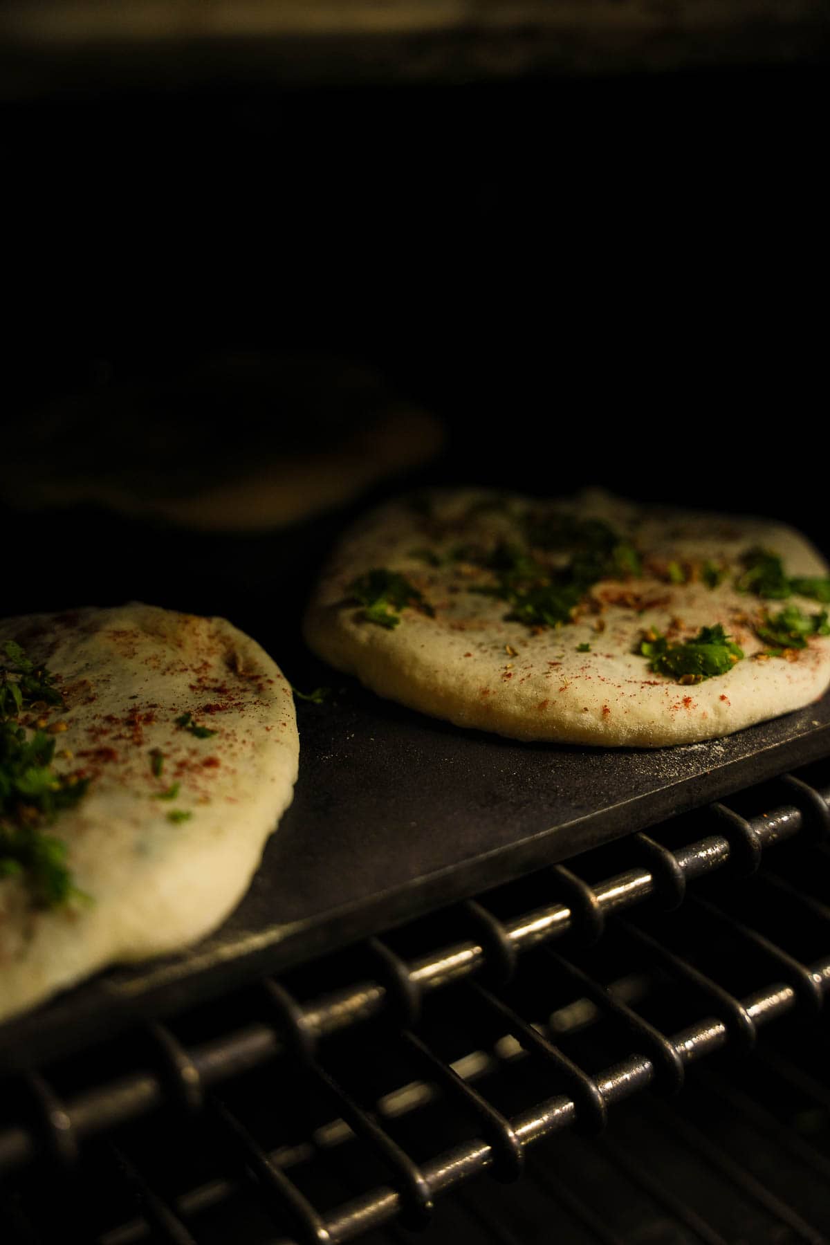 Several breads are baked at the same time on a pizza steel in a hot oven.