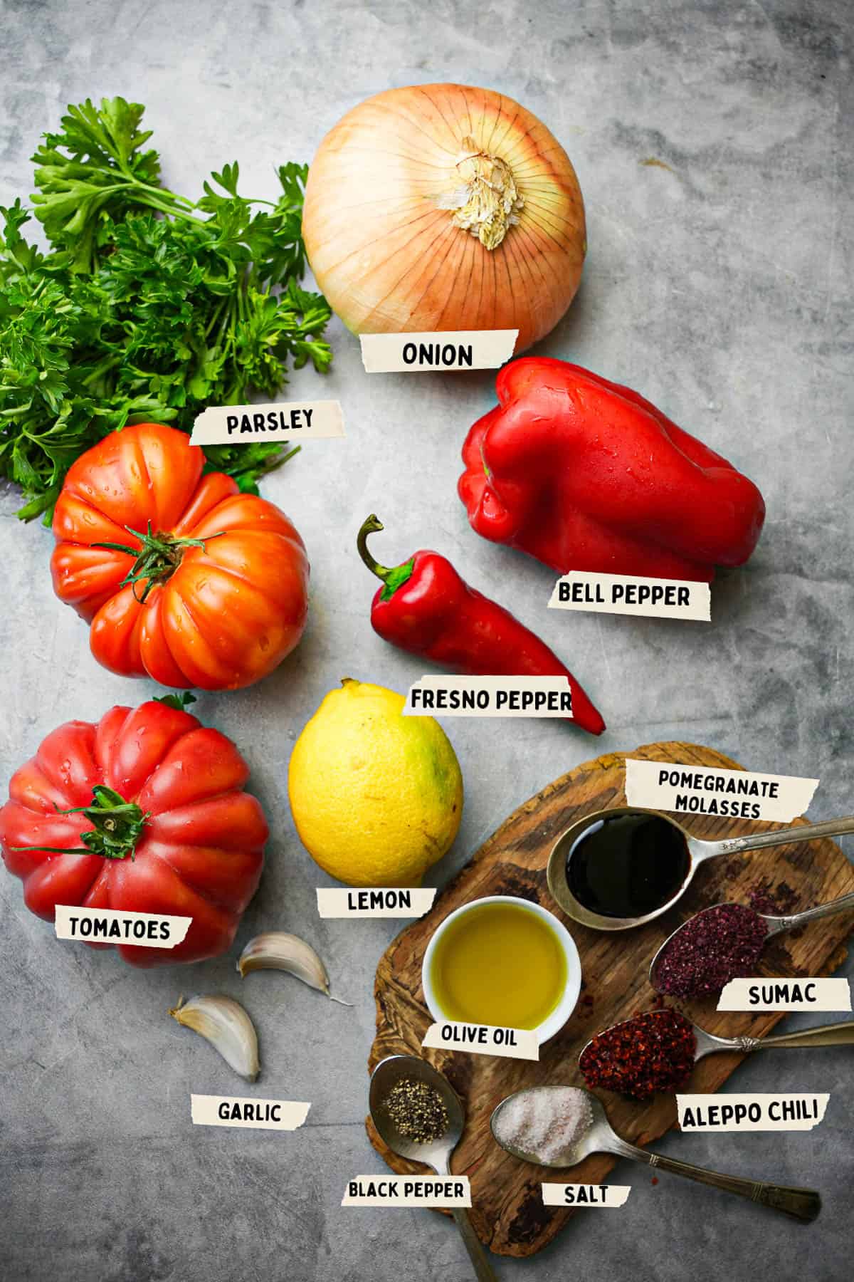 Ingredients for ezme salad are laid out and labeled on a stone countertop.