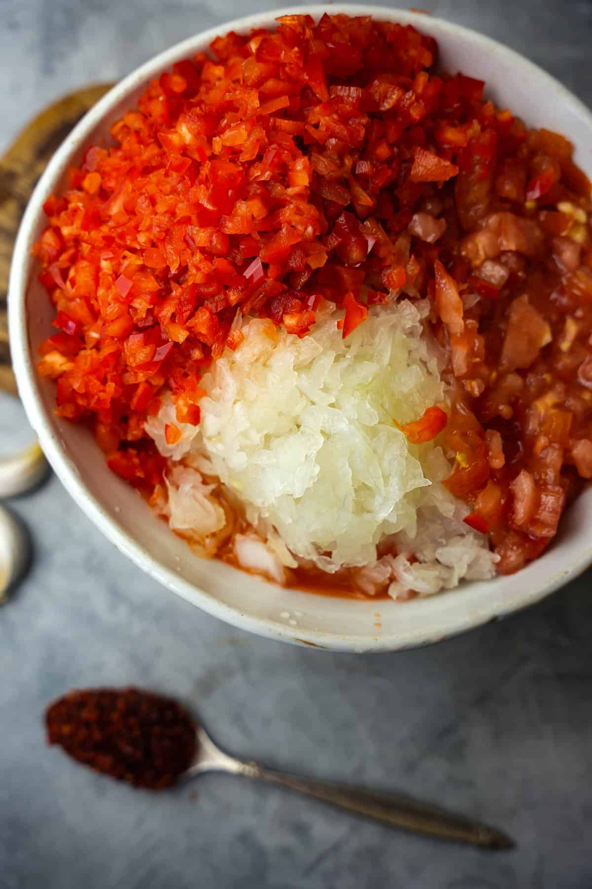 The minced vegetables are assembled in a white ceramic bowl.