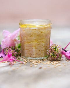 goma dressing in a glass jar surrounded by edible flowers and sesame seeds.