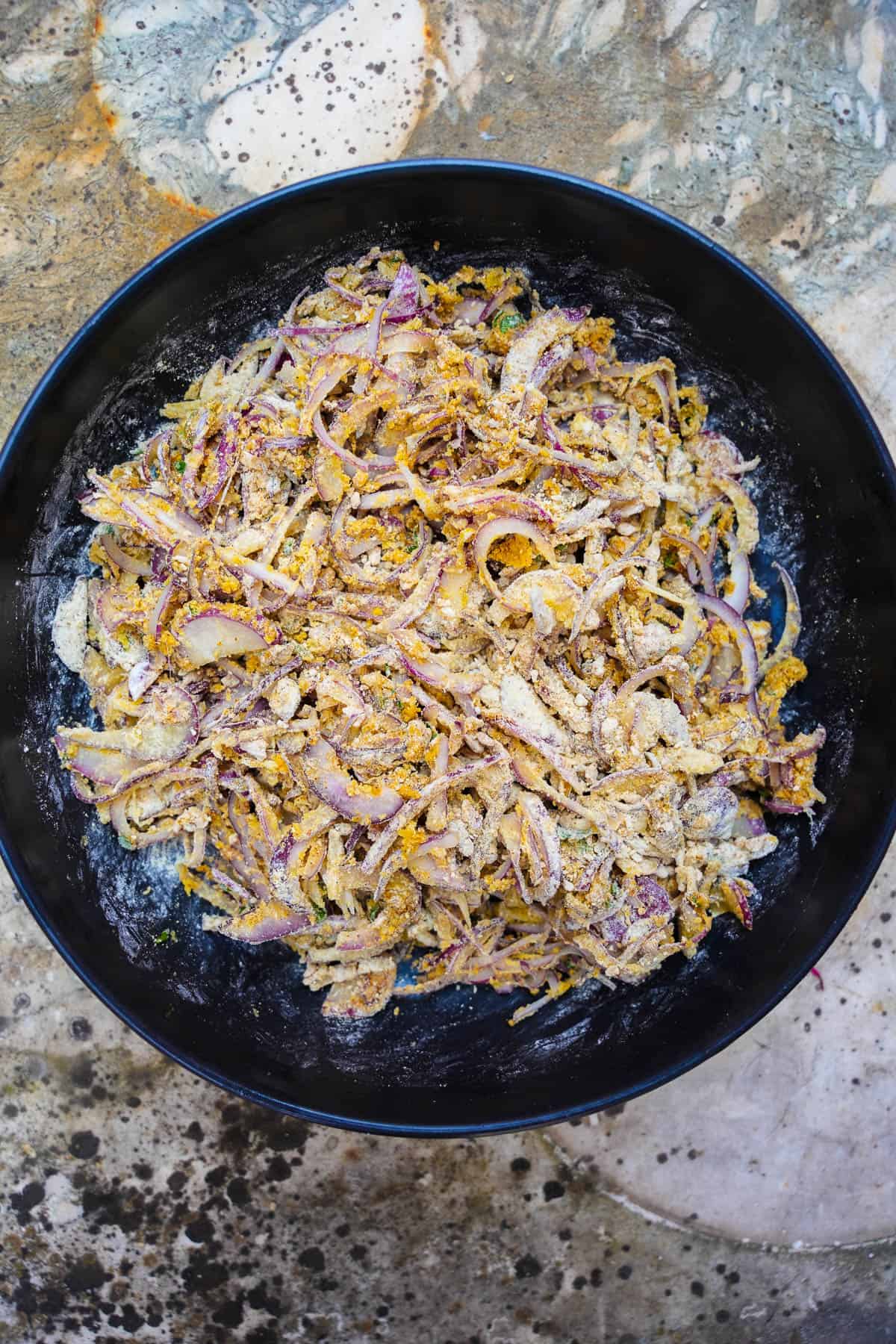 Onions and dry ingredients are squeezed together to form a loose, dry onion dough.