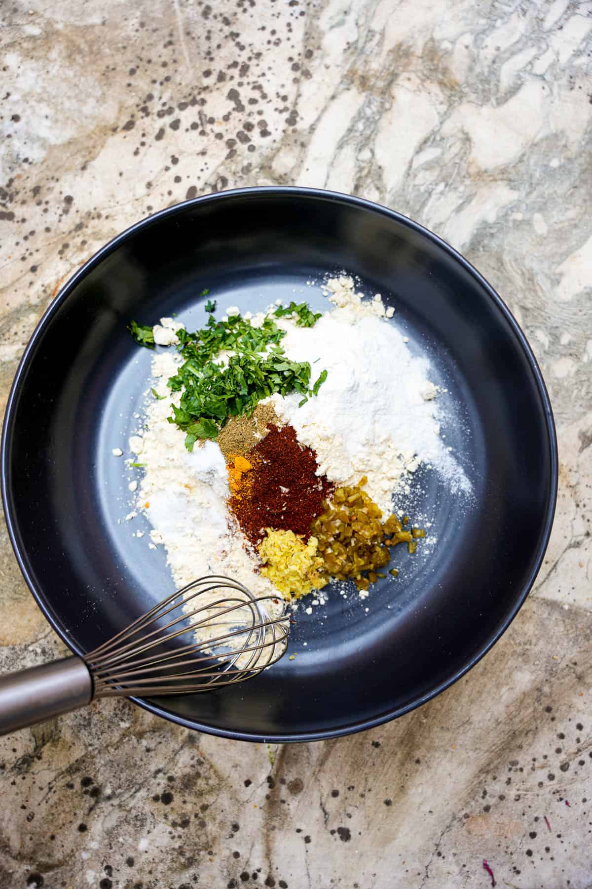 The batter ingredients are mixed in a black bowl with a whisk.