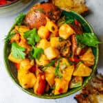 Olive oil braised celery root and vegetables in a green ceramic bowl garnished with fresh herbs.