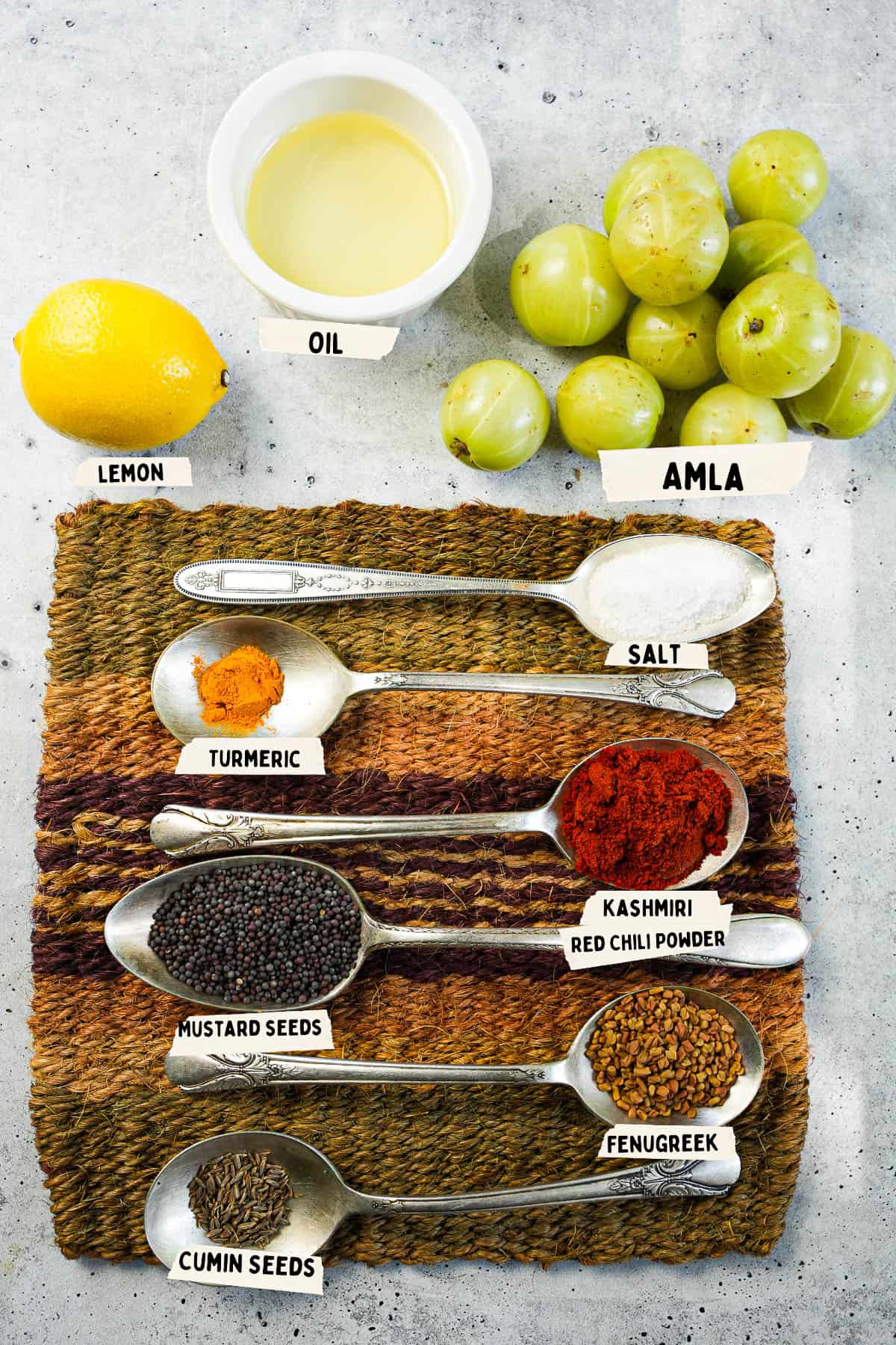 A woven mat with spices and ingredients measured out and labeled for making pickled amla on it.