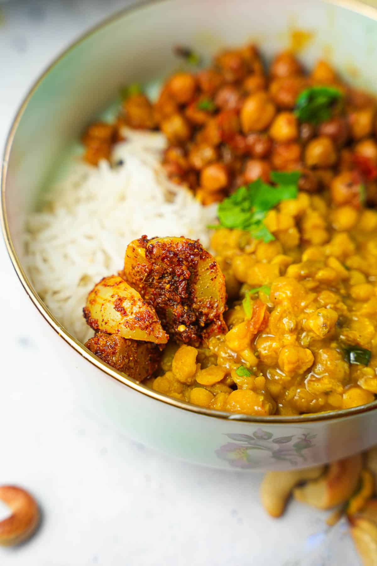A bowl filled with rice and chana dal, kala chana and amla pickle.