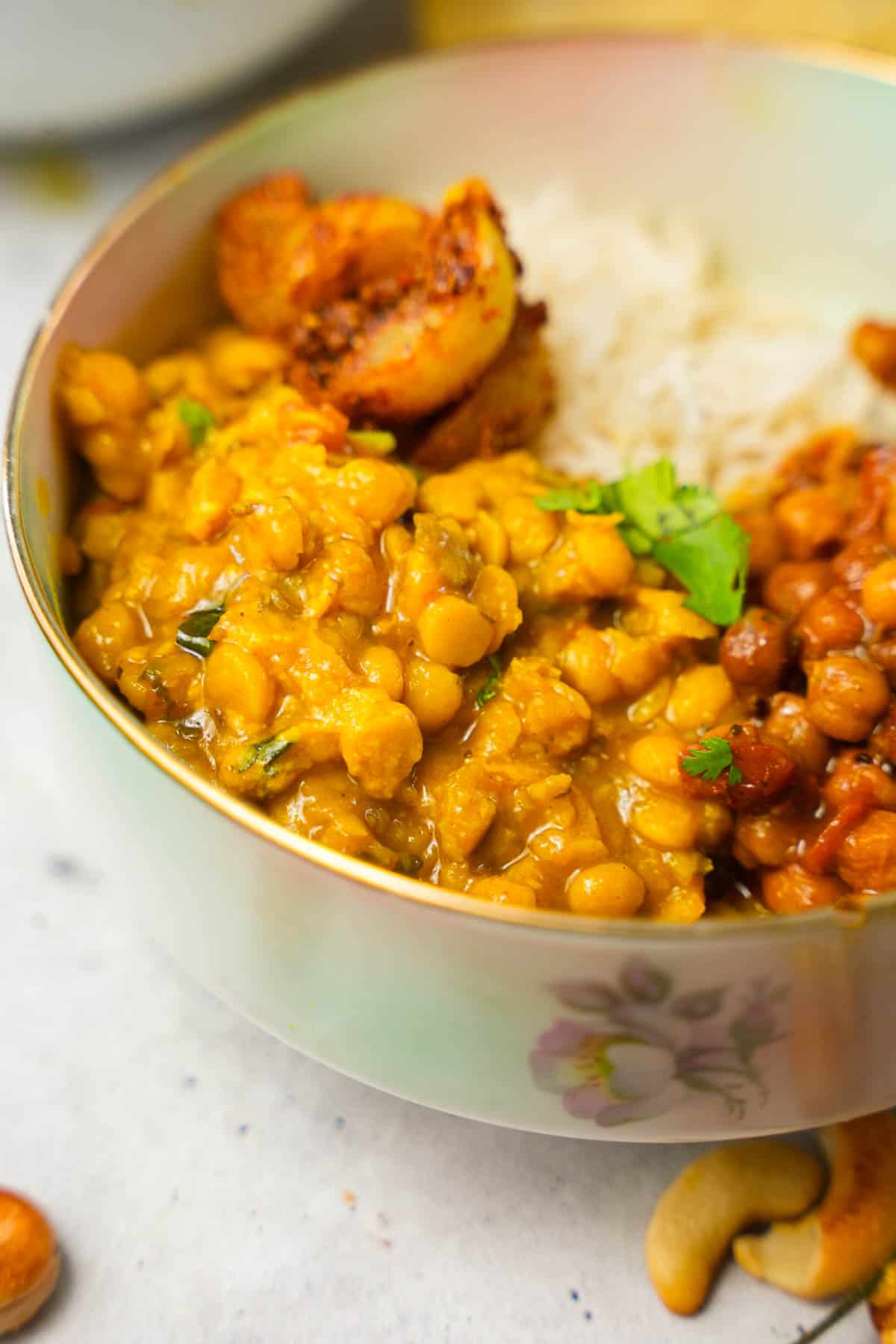 a bowl of chana dal, black chickpea curry with rice and cashews.