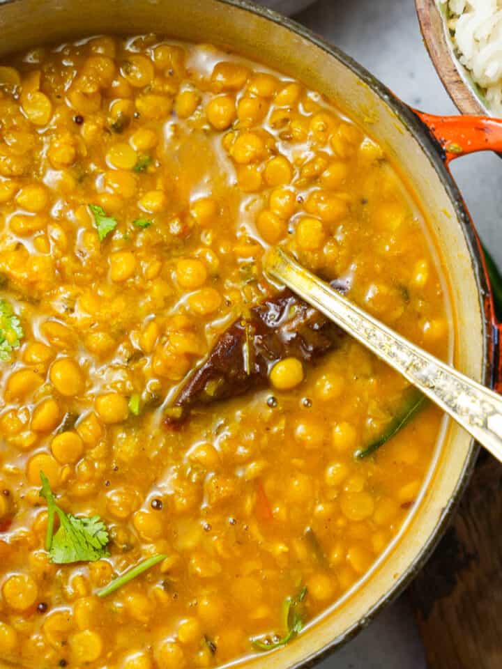 an orange pot of chana dal and rice on a wooden table.