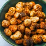 Roasted lotus seeds in a green bowl.