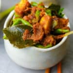 Sambal goreng tempeh in a white ceramic bowl with chopsticks.