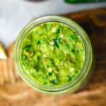 Green shatta sauce in a mason jar on a cutting board.