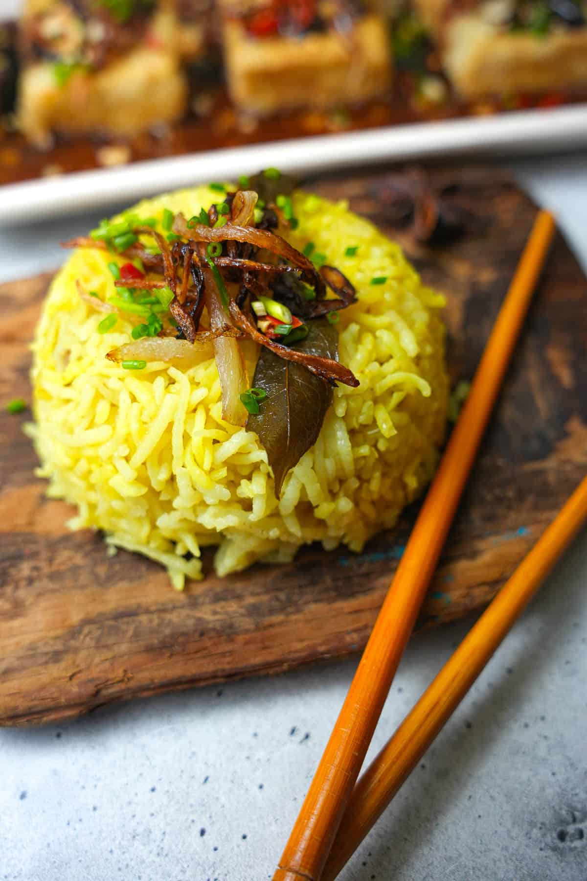 A plate of nasi minyak with chopsticks on it.