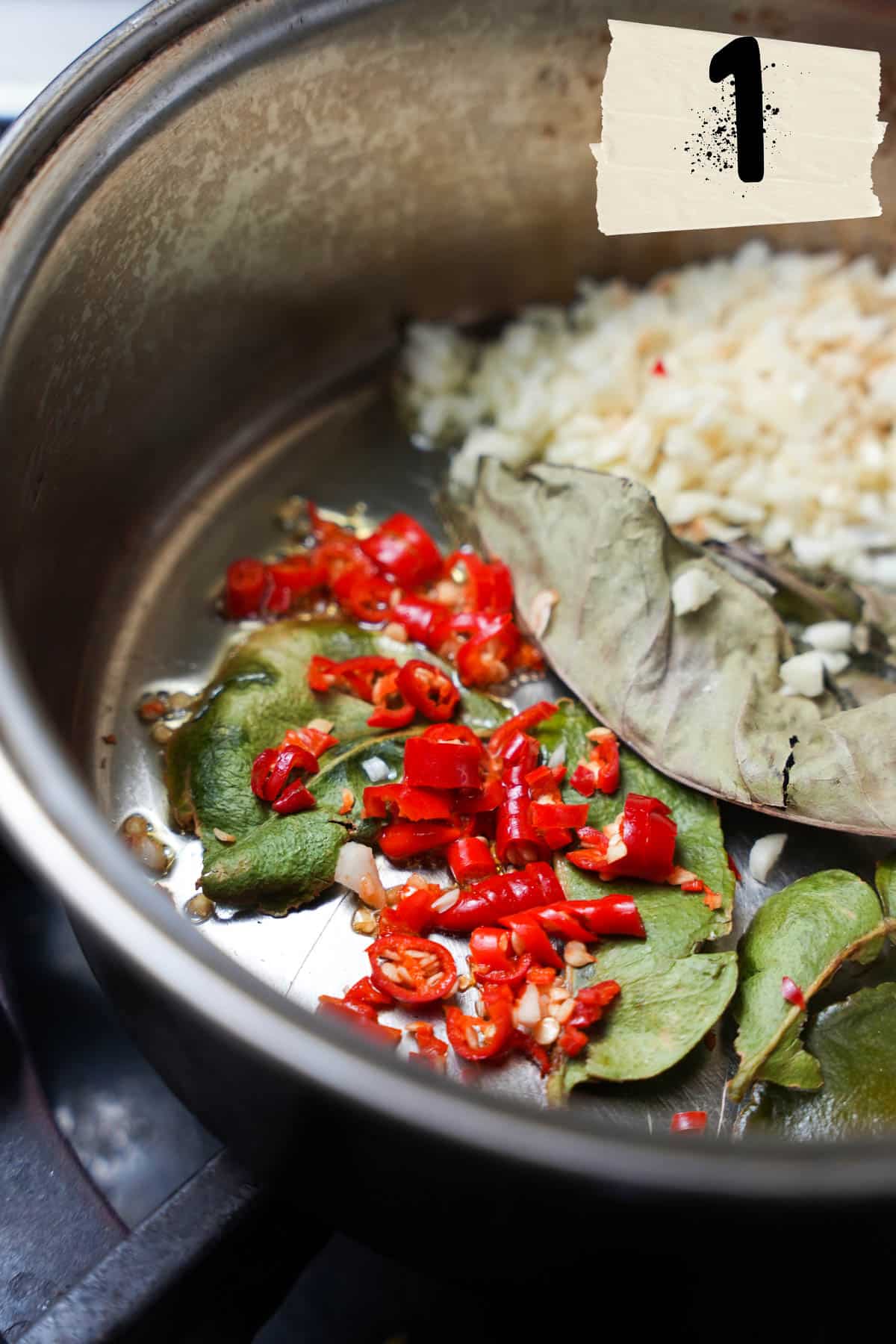 A saucepan full of herbs garlic and spices on a stove.