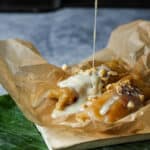 Tupig with thickened coconut milk and peanuts being added to it.