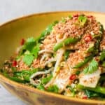 A yellow bowl filled with Urap Sayur topped with tamarind coconut.