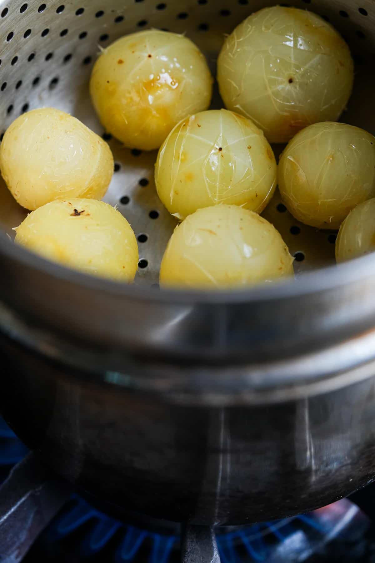 Steamed amla in a metal pot on a stove.