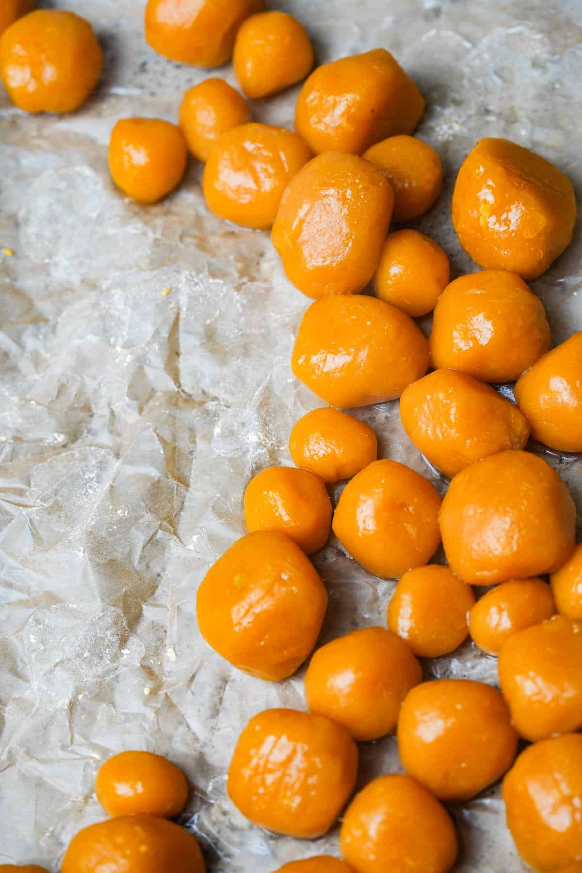 A bunch of cooked sweet potato dumplings of different sizes on a piece of paper.