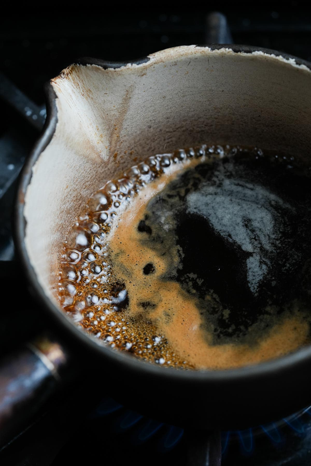 A pan filled with cooking palm sugar syrup on a stove.