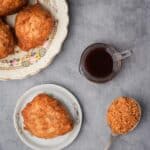 Fried banana fritter on a plate next to a bowl of palm sugar syrup.