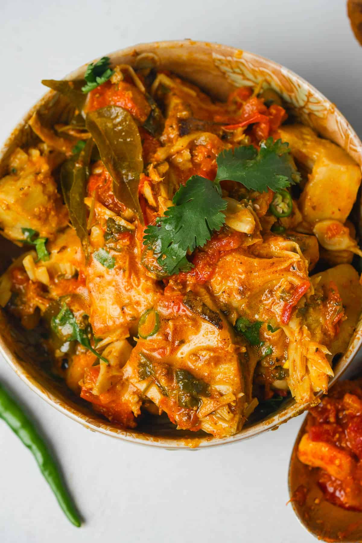 Kathal ki sabji in a red bowl on a table.