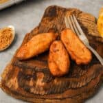 Fried bananas on a wooden cutting board next to a spoonful of palm sugar.