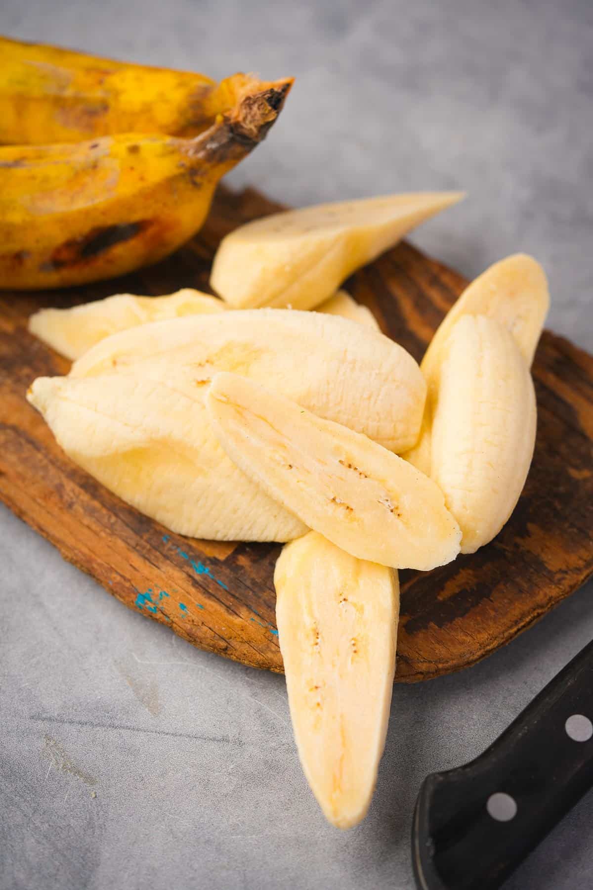 Sliced bananas and a knife on a cutting board.
