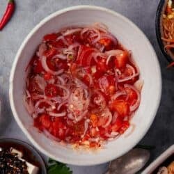 A bowl of sambal dabu dabu with a spoon on a table.