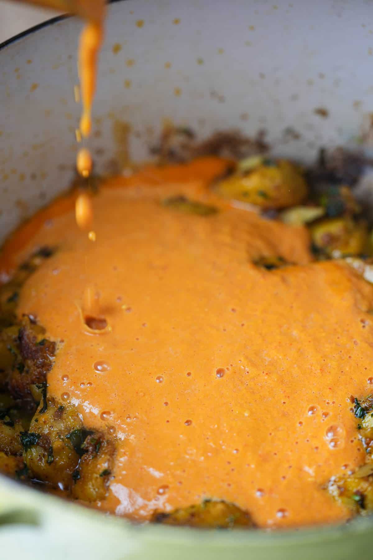 A sauce is being poured over a pot of food.